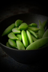 Sugar snaps in a black stone dish bowl.  On a grunge background