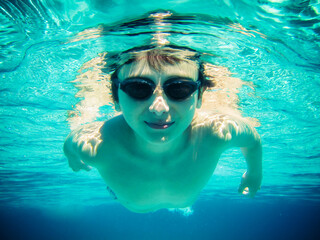 Young Man Swimming Under Water Surface Toward the Camera