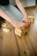 close-up. person stacks wooden blocks of the designer on the floor. children's hands. Board Games. entertainment in the bomb shelter