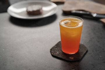 Orange fresh drink with ice in tumbler glass on concrete countertop