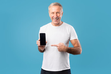 Excited mature man pointing finger at empty smartphone screen