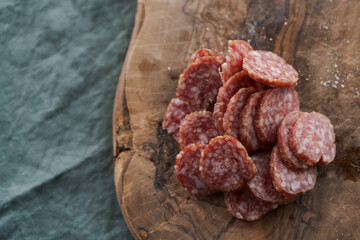 Sliced cured sausage on olive serving board