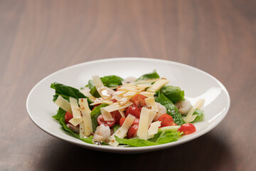 Salad with shrimps, tomatoes and romaine lettuce on white plate