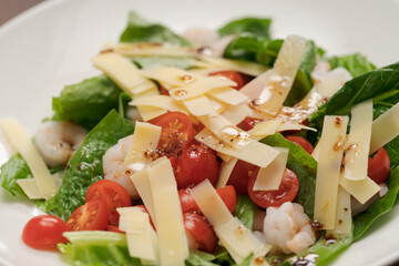 Salad with shrimps, tomatoes and romaine lettuce on white plate