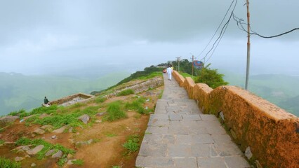4k video of Beautiful view of stairs of Girnar hills with clouds in sky. At Junagadh, Gujarat, india. Mountain covered with fog and green grass during monsoon season. 