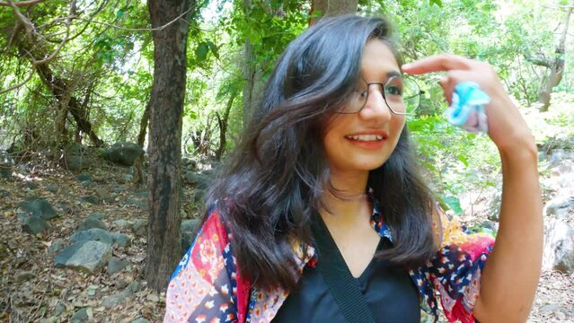 Young Indian Travel Woman Vlogger vlogging in forest of Junagadh with an action camera.  Social media influencer on location in Asia.