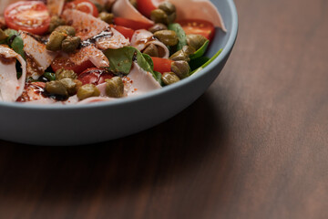 Salad with prosciutto cotto, cherry tomatoes and spinach in blue bowl