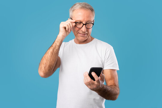 Happy Mature Man Using His Mobile Phone At Studio