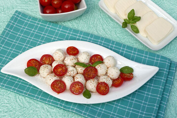 Tomaten mit Mozzarellakugeln auf einem Teller angerichtet.