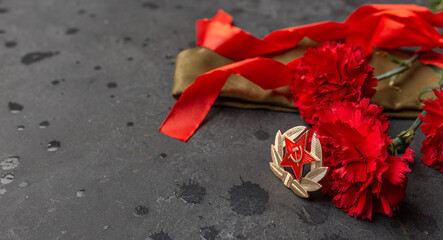 Victory Day, 9 May holiday concept. Carnation flowers, military cap with red ribbon on dark...