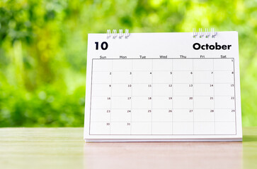 October 2022 Calendar desk for organizer to plan and reminder on wooden table on nature background.