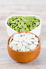 Pumpkin seeds green and unpeeled in wooden bowl.