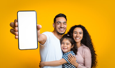 Cheerful Arab Family Demonstrating Blank Smartphone With White Screen, Panorama