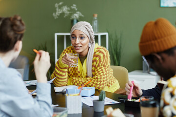 Portrait of creative young woman working with diverse design team at business meeting and enjoying...