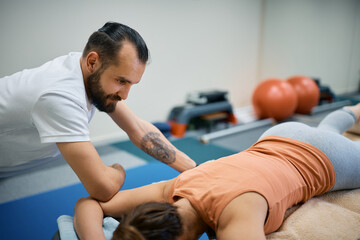 Male physical therapist giving sports massage to a woman at health club. © Drazen