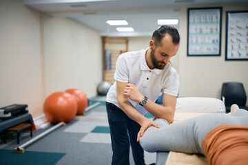 Male therapist massaging athletic woman's leg with his elbow during sports massage.