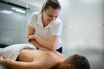 Obraz premium Happy therapist massaging athlete's back with her elbow during sports massage.