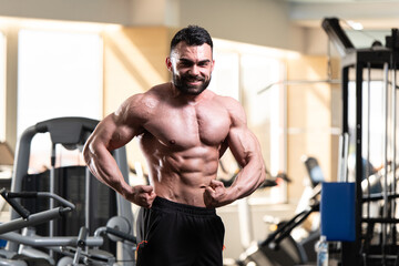 Obraz na płótnie Canvas Muscled Male Model Posing In The Gym