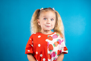 Cute little girl in a red dress on a blue background. The concept of a carefree childhood,...