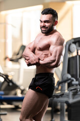 Fototapeta na wymiar Muscled Male Model Posing In The Gym