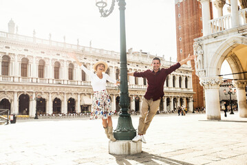 Couple of tourists on vacation in Venice, Italy - Two lovers having fun on city street at sunset -...