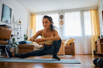 Fototapeta na wymiar Female athlete doing stretching exercise while practicing at home.