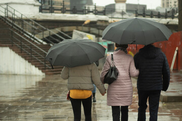 Family in the rain. People with umbrellas on the street. Walk around the city in rainy weather.
