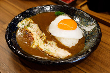 Japanese curry rice with fried egg and grilled pork belly.