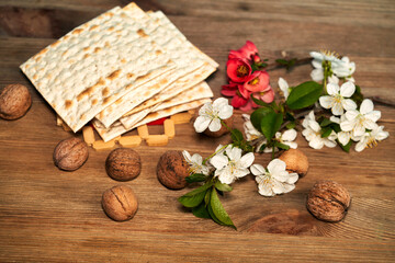 Matzo, nuts and a branch with flowers on a wooden table. Pesah celebration concept (jewish Passover holiday)