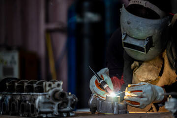 Welder in face mask welds with argon arc stainless steel welding, Industrial worker at the factory...
