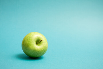 Green apple on blue background. Granny Smith green apple.