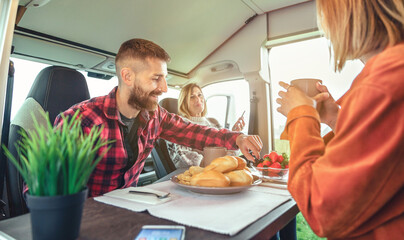 Happy friends having breakfast in a camper van in the morning