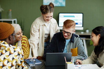 Portrait of diverse creative team using laptop in business meeting enjoying work on project together