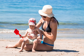 woman on the beach with little boy playing