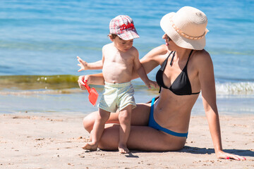 woman on the beach with little boy playing