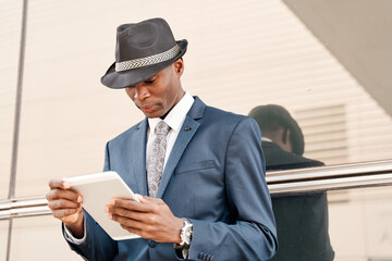 portrait of a young businessman in a suit and hat using a tablet pc