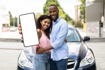 Happy black couple using showing smartphone with empty screen