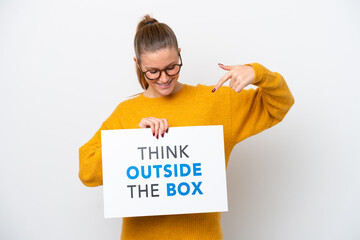 Young caucasian woman isolated on white background holding a placard with text Think Outside The Box and  pointing it