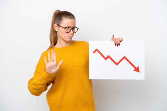 Young caucasian woman isolated on white background holding a sign with a decreasing statistics arrow symbol and doing stop sign