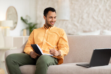 Portrait of smiling Arabic man using laptop and writing