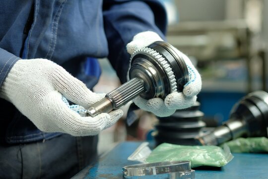Maintenance and repair of cars. A joint of equal angular velocities. Close-up. The mechanic inspects and controls the compliance and integrity of the new spare part.