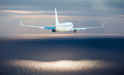 Airplane flying over tropical sea at sunset