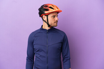 Young Brazilian cyclist man isolated on purple background looking to the side - obrazy, fototapety, plakaty