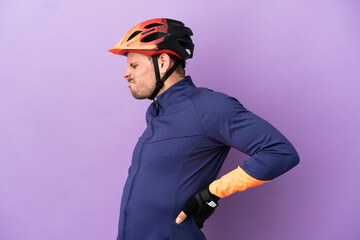 Young Brazilian cyclist man isolated on purple background suffering from backache for having made an effort