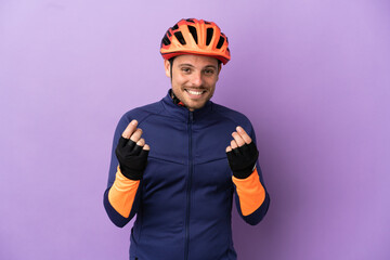 Young Brazilian cyclist man isolated on purple background making money gesture