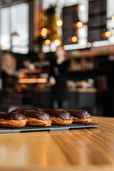 Tasty chocolate eclairs on slate plate in cafe. Delicious pastries for coffee. Isolated eclairs on the wood table