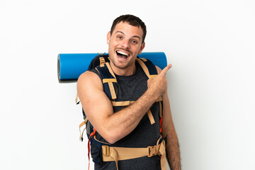 Brazilian mountaineer man with a big backpack over isolated white background surprised and pointing side