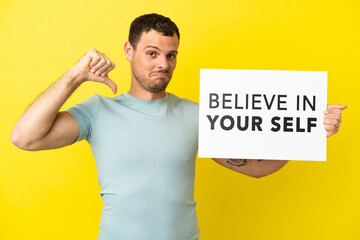 Brazilian man over isolated purple background holding a placard with text Believe In Your Self with proud gesture