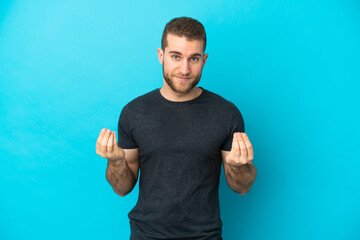 Young handsome caucasian man isolated on blue background making money gesture but is ruined