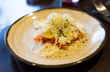 mix of tomatoes, cheese, eggs with mayonnaise on a plate in a restaurant